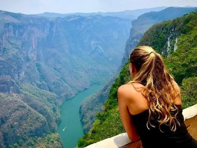 Woman looking over a wall into the deep river valley of Sumidero Canyon