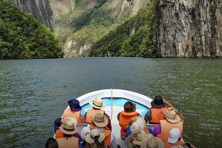 Tourists wearing life jackets and hats on a boat in Sumidero Canyon.