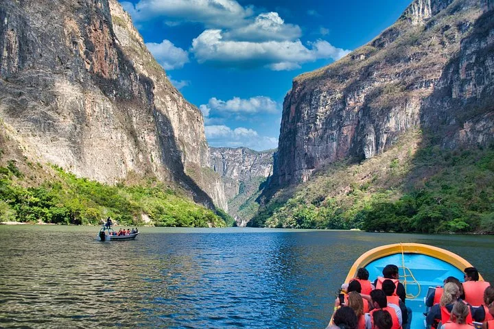 Tourists on boats traversing the waters of Sumidero Canyon between massive vertical cliffs