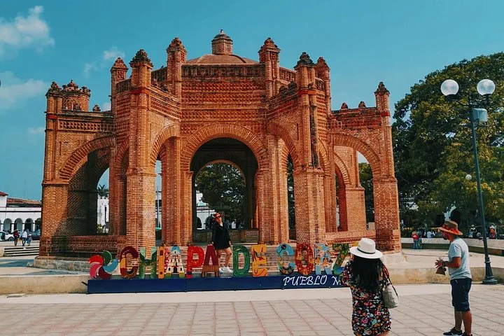Tourists posing by colorful letters in front of the historic La Pila fountain
